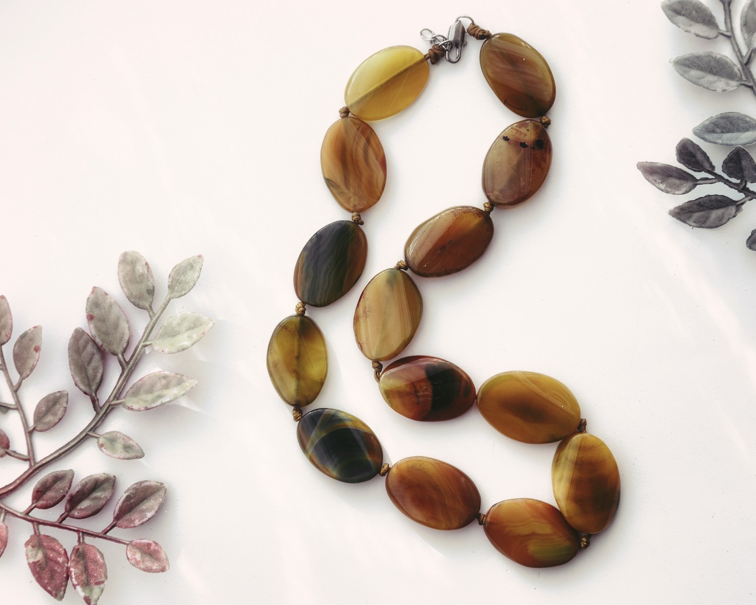 Two necklaces of different shapes and colors on a white surface